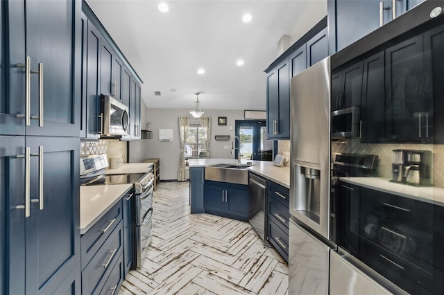 kitchen with stainless steel appliances, a peninsula, a sink, light countertops, and decorative backsplash