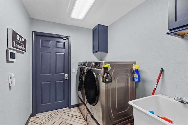 clothes washing area featuring cabinet space, a sink, and washing machine and clothes dryer