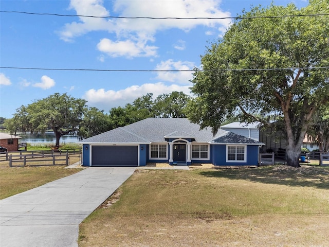 ranch-style home with a front lawn, a water view, and a garage