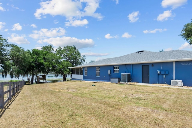 rear view of property with cooling unit, fence, a sunroom, a yard, and stucco siding