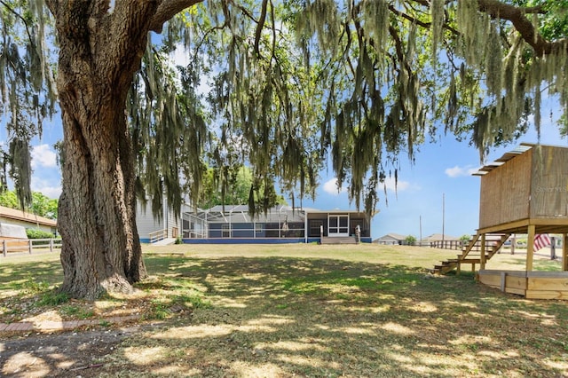 view of yard featuring a sunroom, glass enclosure, fence, and stairs