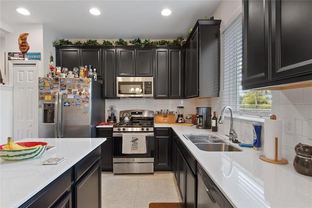 kitchen featuring appliances with stainless steel finishes, sink, backsplash, and light tile flooring