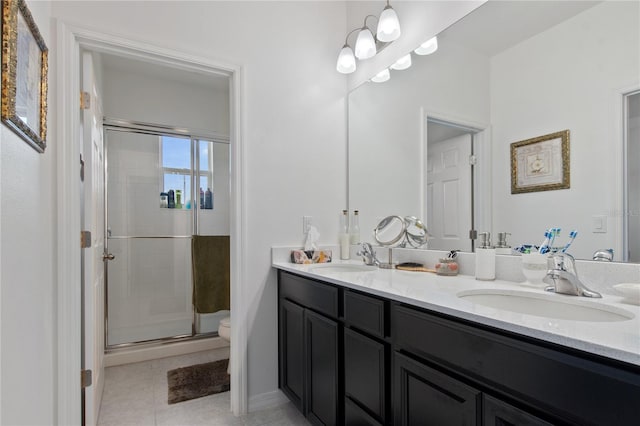 bathroom featuring dual sinks, tile flooring, vanity with extensive cabinet space, a shower with door, and toilet