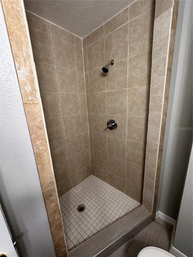 bathroom with a tile shower and toilet