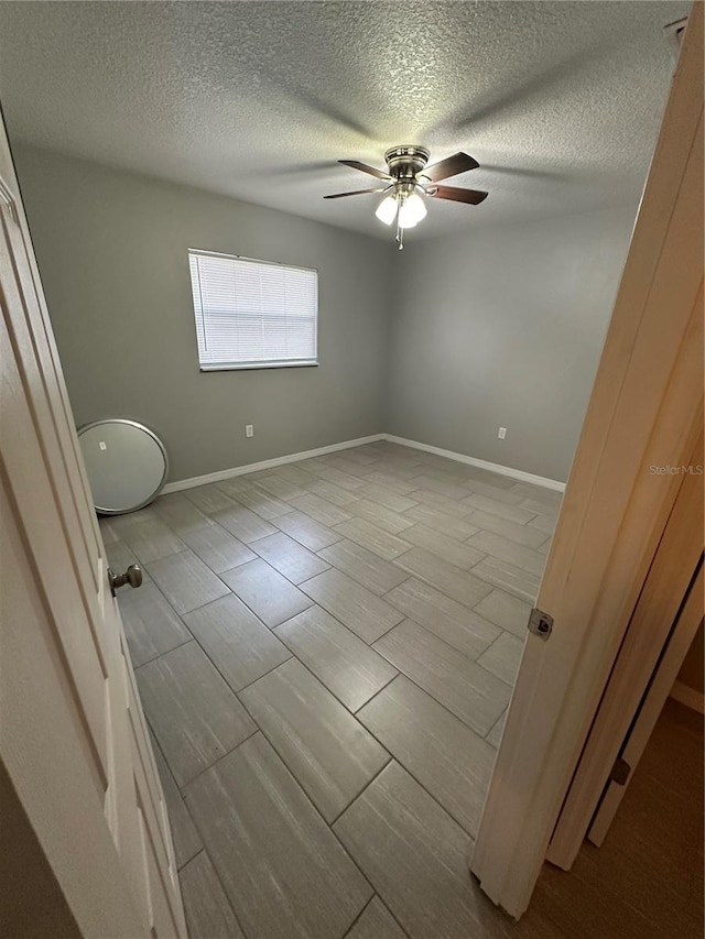 empty room featuring a textured ceiling, ceiling fan, and tile floors