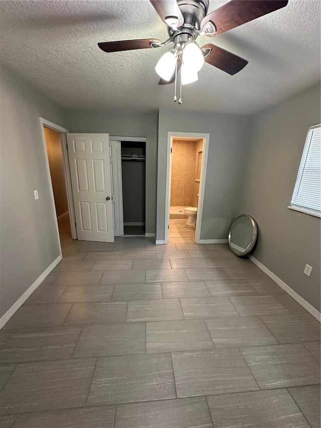 unfurnished bedroom with tile floors, a textured ceiling, ceiling fan, and ensuite bath