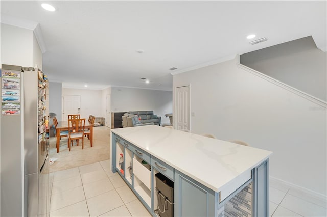 kitchen featuring a center island, crown molding, light tile patterned floors, blue cabinetry, and stainless steel refrigerator