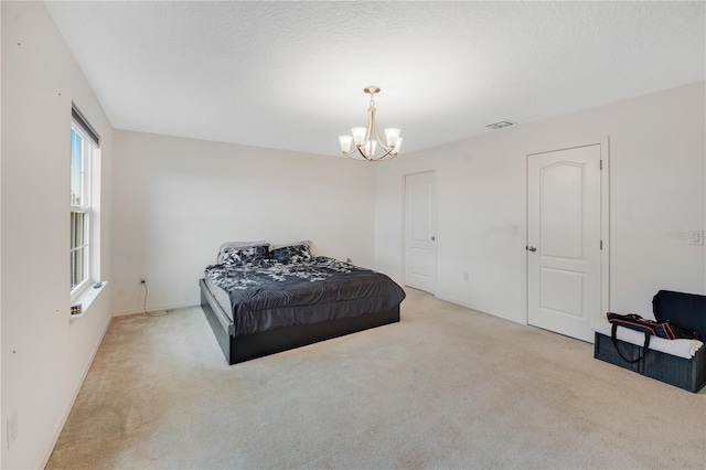 bedroom with a textured ceiling, light carpet, and a chandelier