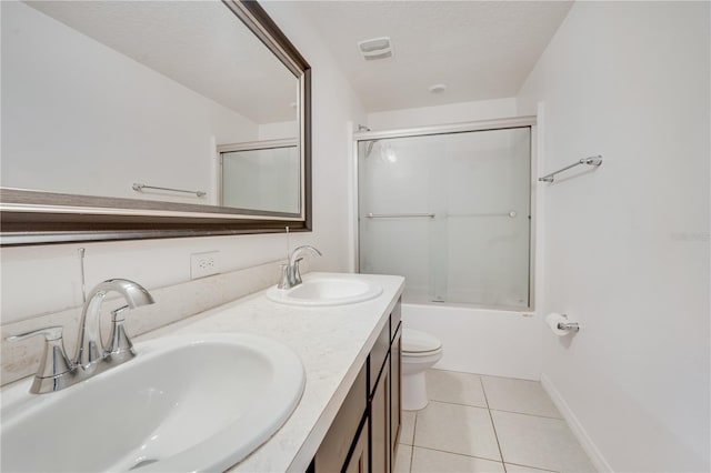 full bathroom featuring tile patterned flooring, bath / shower combo with glass door, a textured ceiling, toilet, and vanity