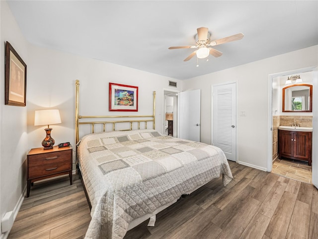 bedroom with ceiling fan, a closet, hardwood / wood-style flooring, sink, and connected bathroom