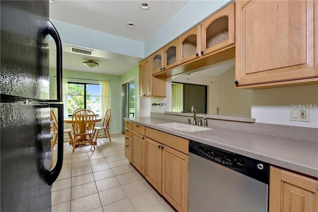 kitchen featuring light brown cabinets, stainless steel dishwasher, light tile flooring, black fridge, and sink