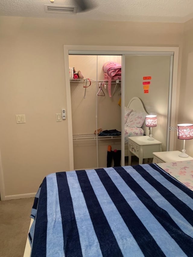 carpeted bedroom featuring a textured ceiling and a closet