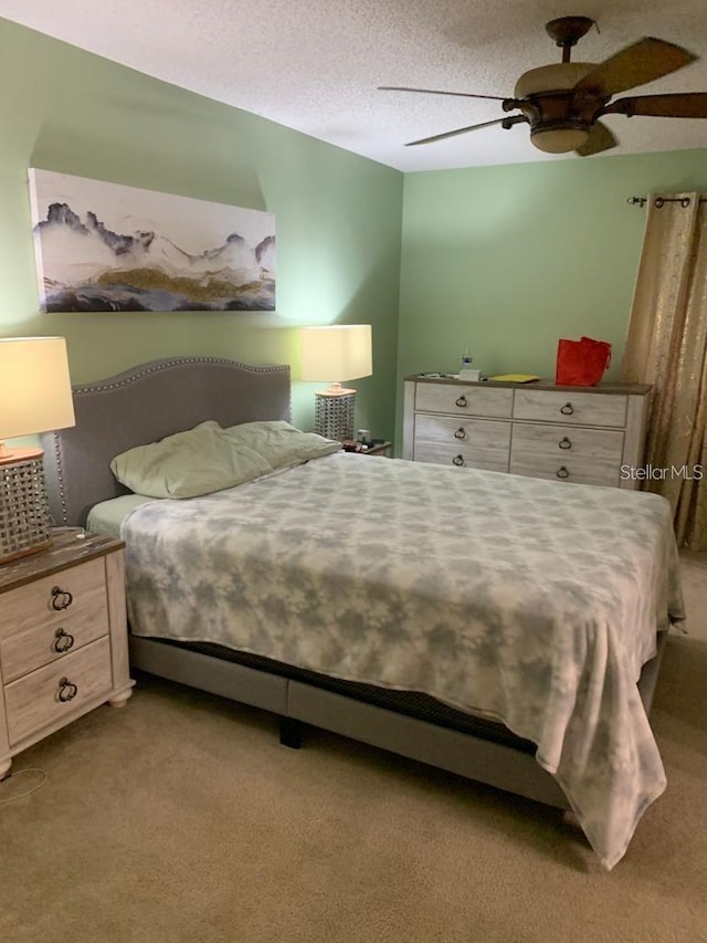 bedroom featuring light colored carpet, ceiling fan, and a textured ceiling