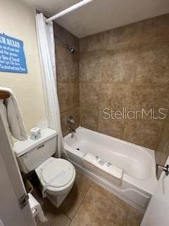 bathroom with tile floors, shower / tub combo, and toilet