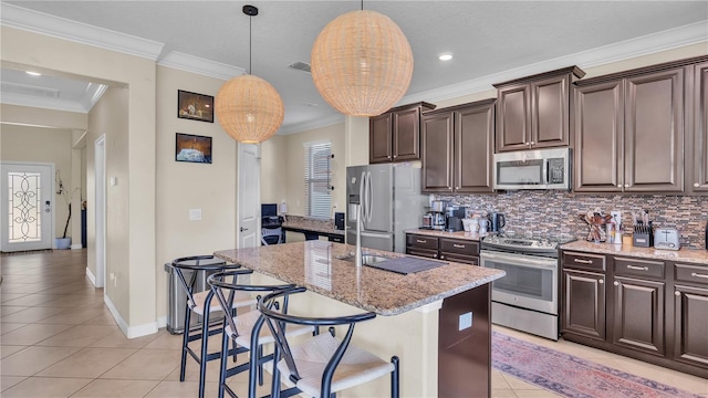 kitchen featuring stainless steel appliances, tasteful backsplash, light stone countertops, a kitchen island with sink, and light tile patterned floors