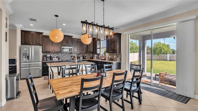 dining space featuring sink, crown molding, and light tile patterned floors