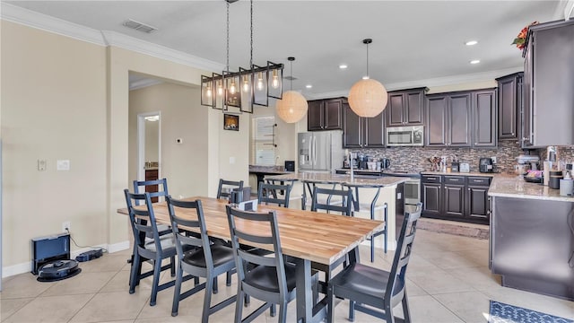 dining room with sink, crown molding, and light tile patterned flooring