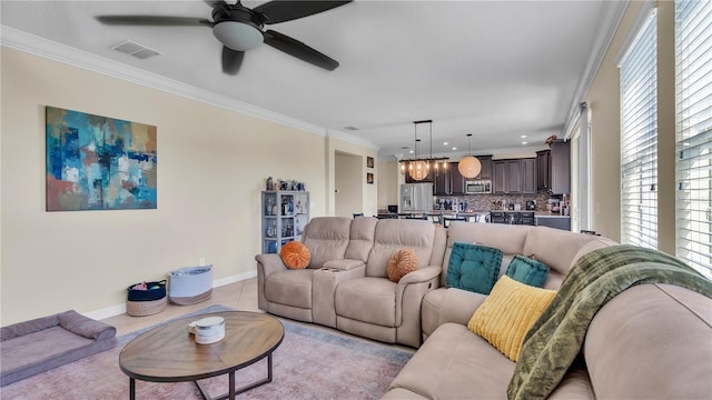 living room featuring ceiling fan, crown molding, a healthy amount of sunlight, and light tile patterned floors