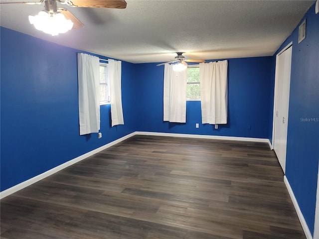 unfurnished room with a textured ceiling, dark wood-type flooring, and ceiling fan