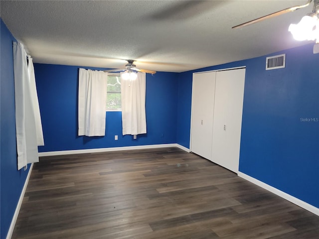 unfurnished bedroom featuring dark wood-type flooring, a closet, ceiling fan, and a textured ceiling