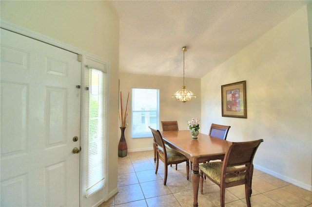 tiled dining area featuring a notable chandelier and vaulted ceiling