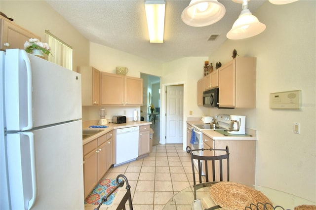 kitchen with white appliances, a textured ceiling, light brown cabinetry, decorative light fixtures, and light tile patterned flooring