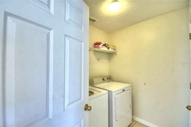 washroom with washer and clothes dryer and a textured ceiling