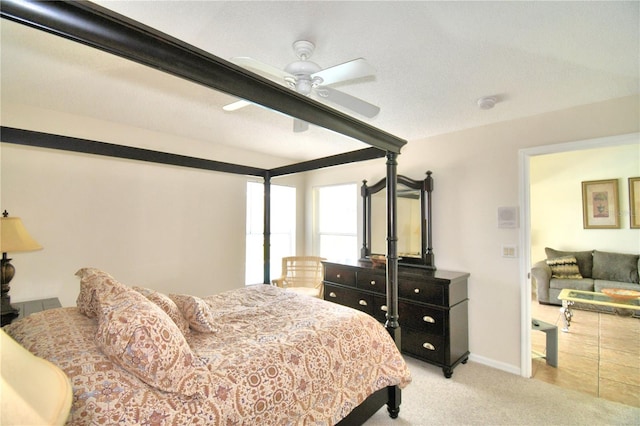 bedroom with ceiling fan, light colored carpet, and a textured ceiling