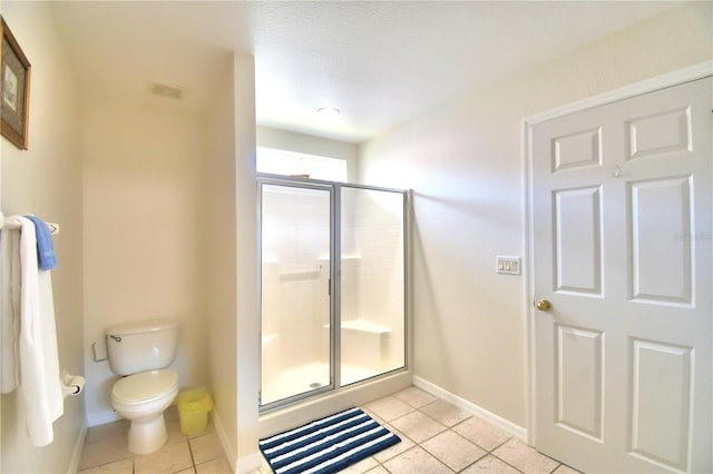 bathroom featuring a textured ceiling, tile patterned flooring, an enclosed shower, and toilet