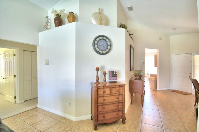 corridor featuring light tile patterned flooring and high vaulted ceiling