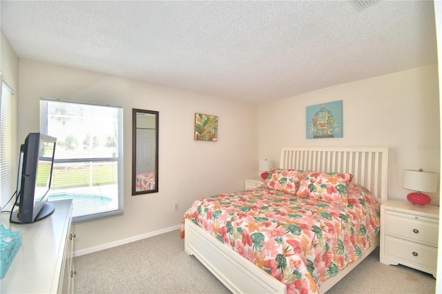 bedroom with a textured ceiling and light colored carpet