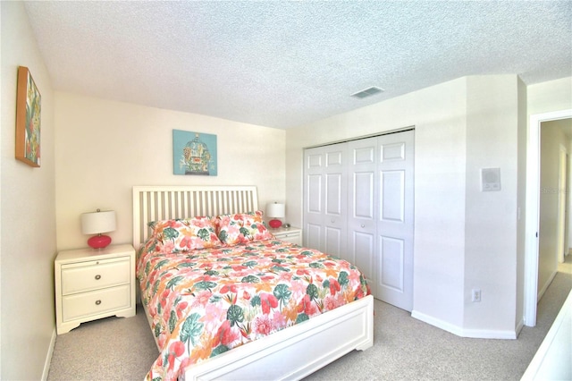 bedroom featuring light carpet, a textured ceiling, and a closet