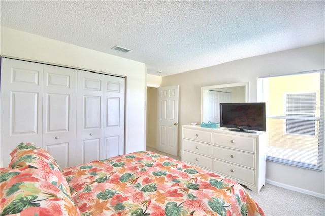 bedroom featuring light carpet, a closet, and a textured ceiling