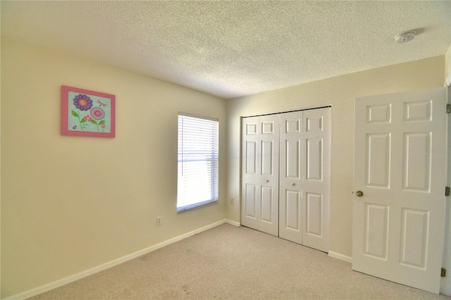 unfurnished bedroom with a textured ceiling, light colored carpet, and a closet