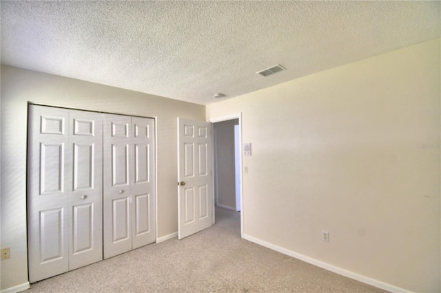 unfurnished bedroom with light colored carpet, a textured ceiling, and a closet