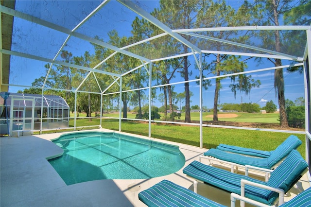 view of swimming pool featuring glass enclosure, a patio area, and a yard