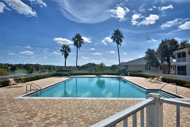 view of pool with a water view and a patio area