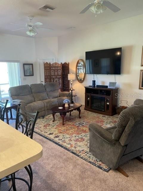 carpeted living room with a fireplace and ceiling fan