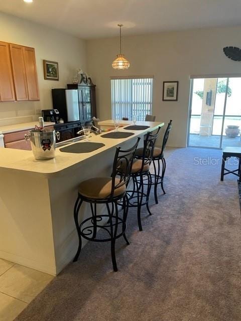 kitchen with light carpet, a kitchen breakfast bar, and decorative light fixtures