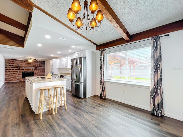 kitchen with dark wood-type flooring, stainless steel fridge, pendant lighting, a breakfast bar, and white cabinets