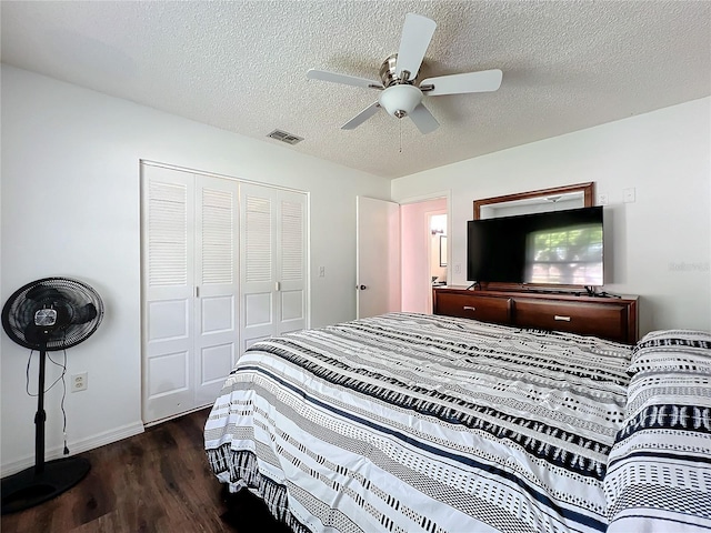 bedroom with a textured ceiling, ceiling fan, dark wood-type flooring, and a closet