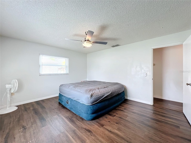 bedroom with a textured ceiling, ceiling fan, and dark hardwood / wood-style floors