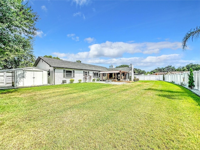 rear view of house with a storage shed, a yard, and a patio