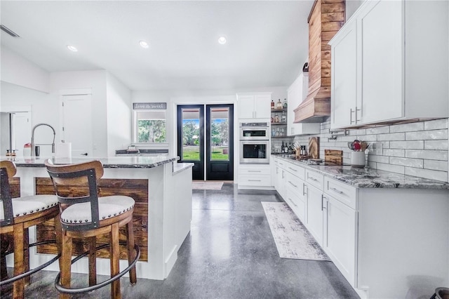 kitchen featuring white cabinetry, light stone counters, and decorative backsplash