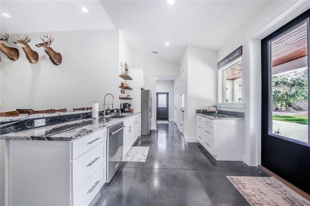 kitchen with stainless steel appliances, sink, white cabinets, and dark stone counters