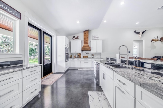 kitchen featuring vaulted ceiling, sink, white cabinets, custom exhaust hood, and stainless steel dishwasher