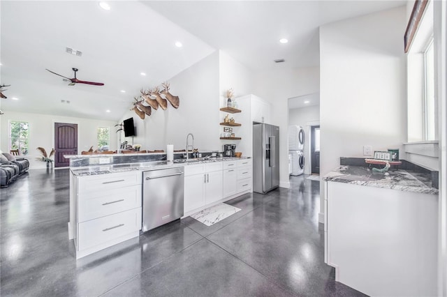 kitchen with appliances with stainless steel finishes, washer / dryer, kitchen peninsula, and white cabinets