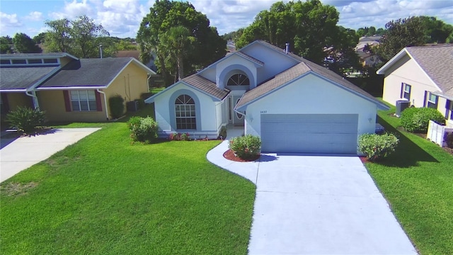 view of front of house featuring a garage, driveway, a front yard, and stucco siding