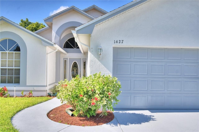 doorway to property with an attached garage and stucco siding