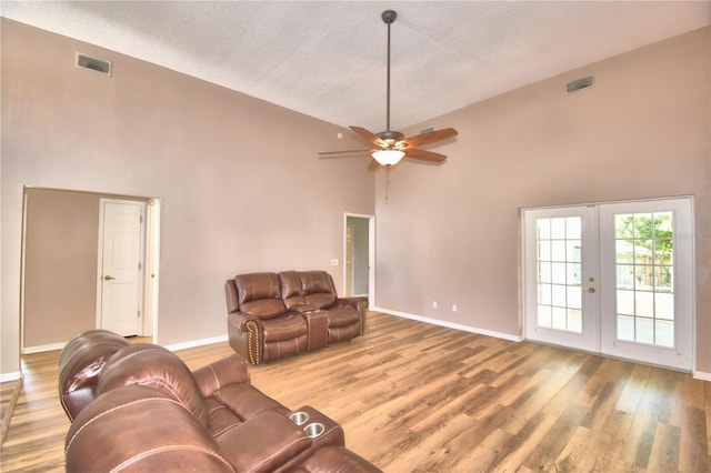 living room featuring baseboards, visible vents, wood finished floors, french doors, and high vaulted ceiling